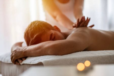 Massage therapist doing back massage on man body .
